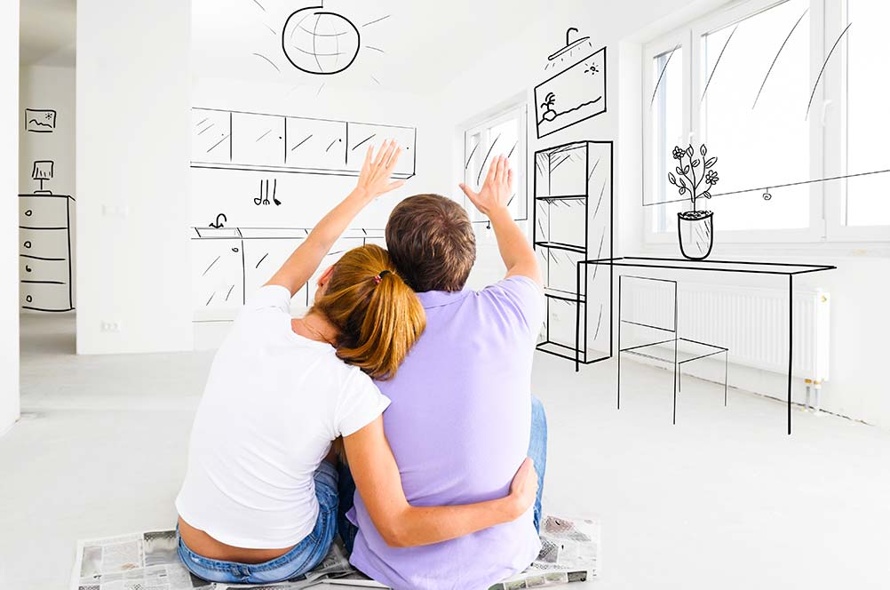 Young couple sitting on the floor visualizing a home remodel with an FHA 203K mortgage refinancing option.