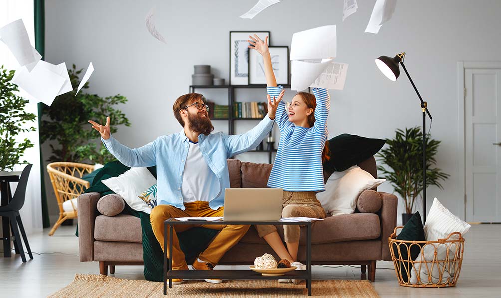 A happy couple throwing papers in the air after discovering mortgage refinance possibilities.