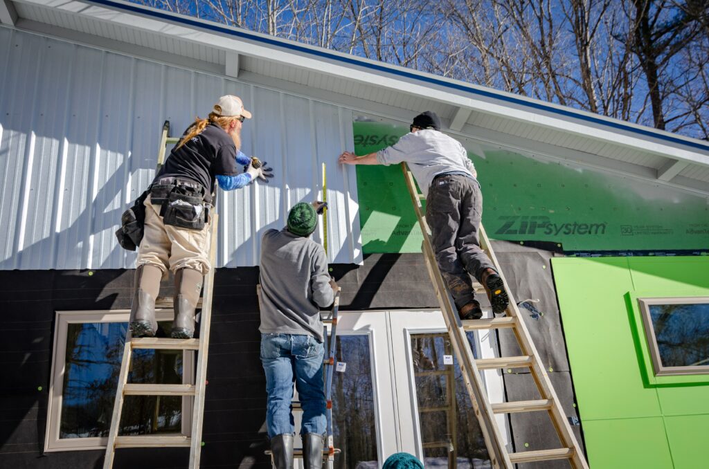 Modular vs Manufactured homes, three men on ladders putting up siding 